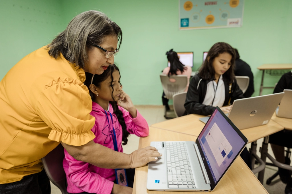 Jilma Serrano ajuda a sua aluna Andrea Florez. Os professores praticam a utilização do equipamento e aprendem metodologias inovadoras que utilizam a tecnologia para melhorar o ensino.